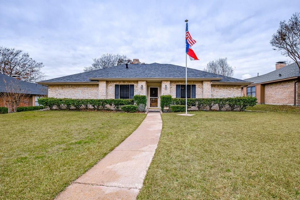 Before: tan brick ranch house with dark shutters and overgrown hedges