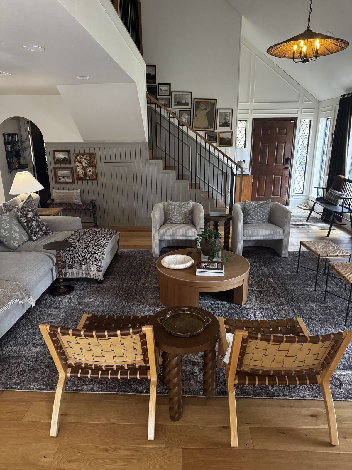 Living room with vaulted ceiling, gallery wall along the staircase, and layered rugs