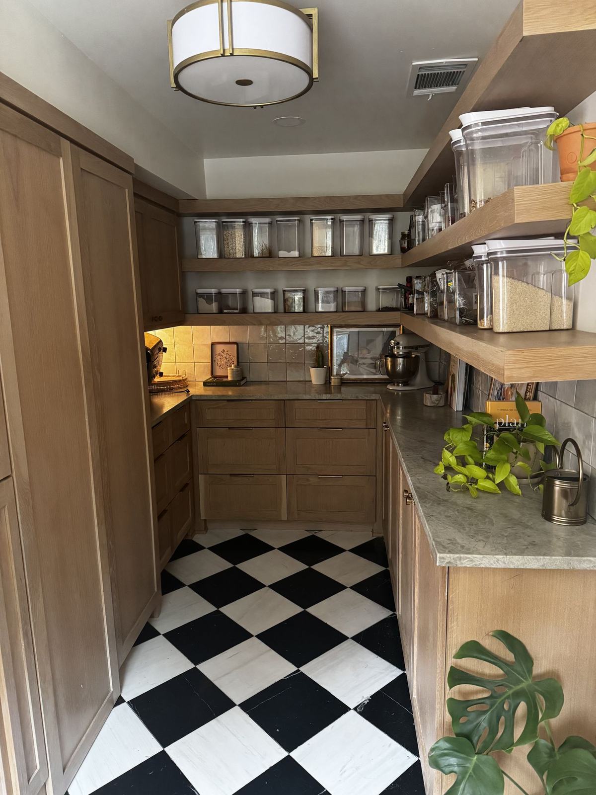 Walk-in pantry with checkerboard floor, oak cabinetry and open shelving