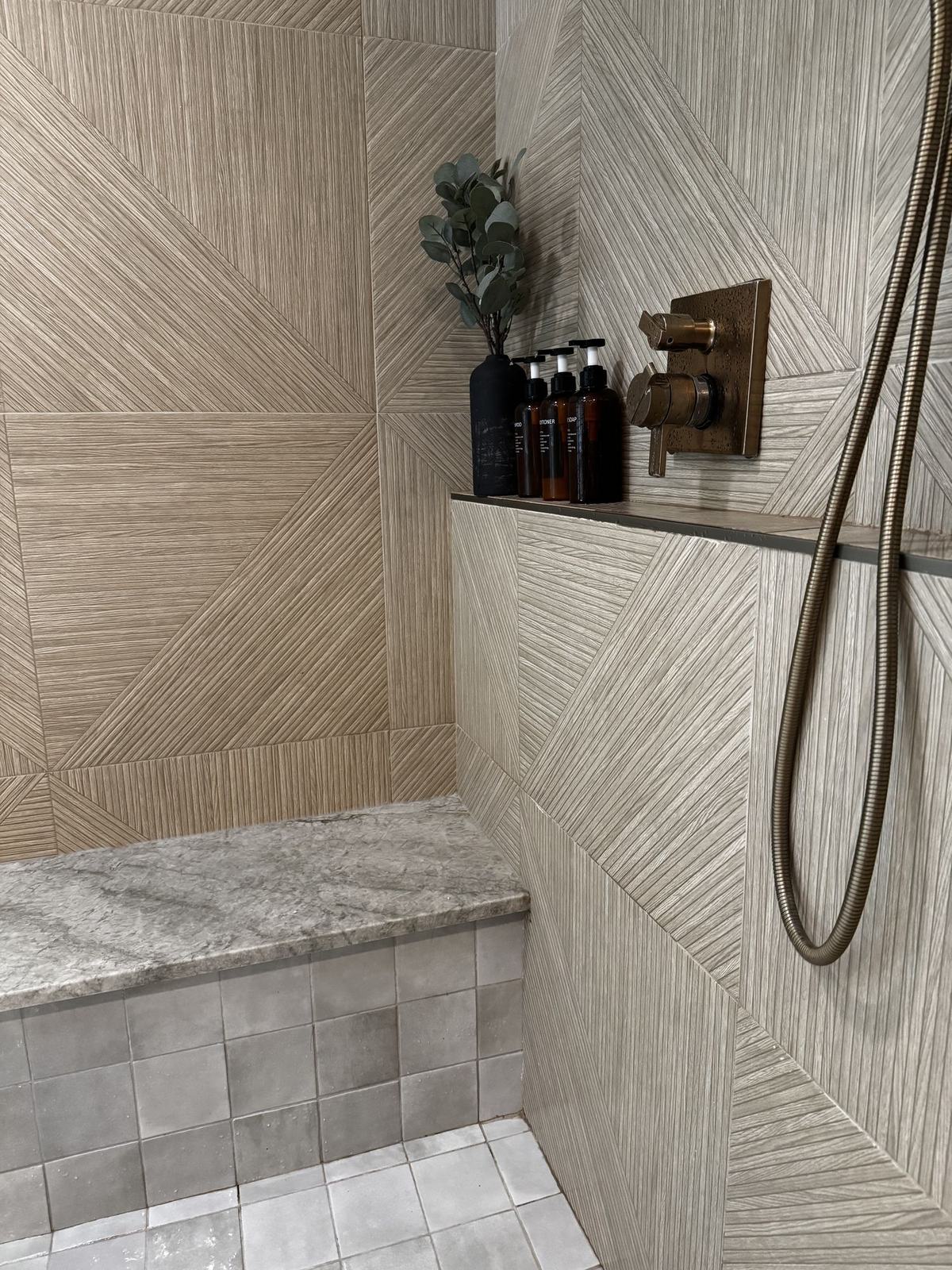 Shower with fluted geometric tile, stone bench and unlacquered brass fixtures