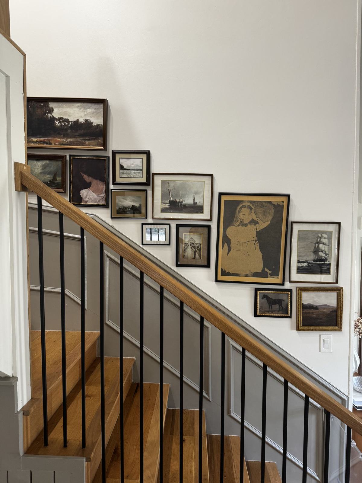 Staircase gallery wall of vintage oil paintings and framed prints