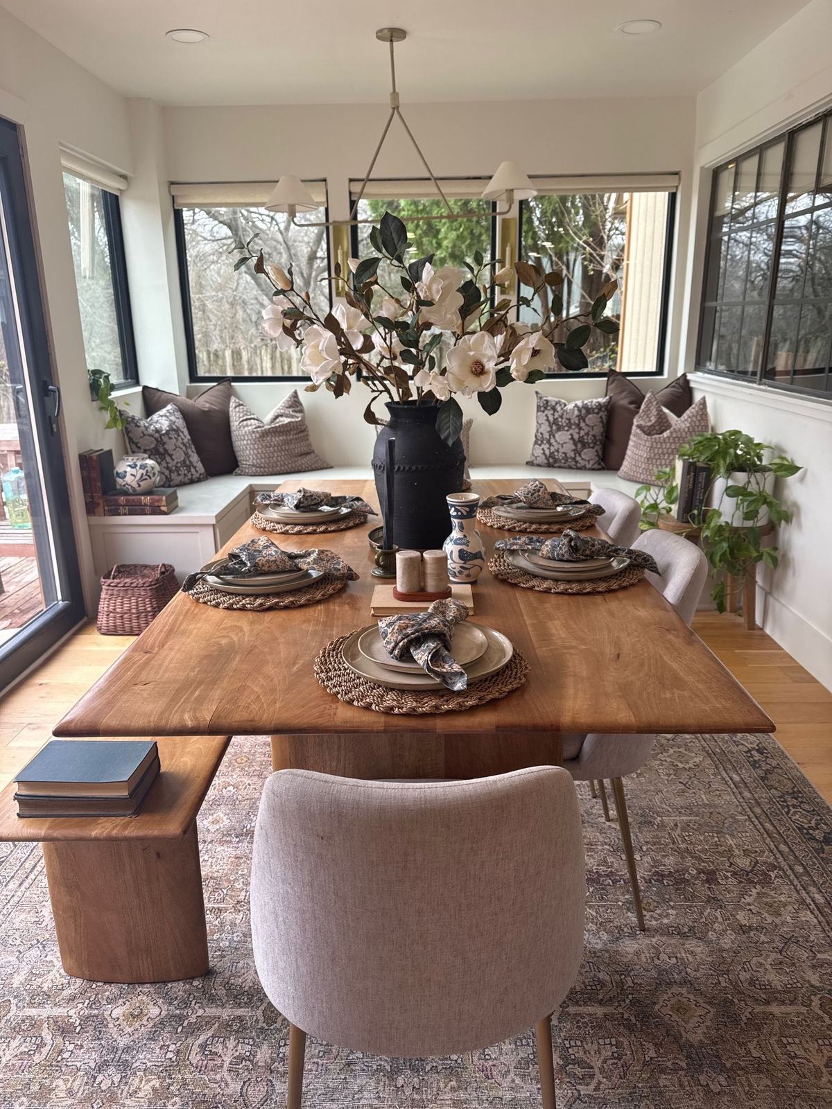 Breakfast nook with live-edge table, built-in banquette, patterned pillows and magnolia branches