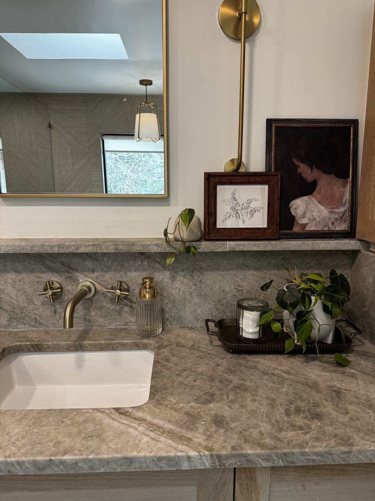 Bathroom vanity with quartzite counter and backsplash, wall-mounted brass faucet, antique portrait